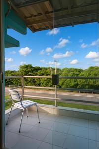 a chair on a balcony with a view of a road at Pousada Recanto dos Pássaros in Linhares