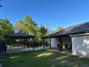 a pavilion with a table and chairs in a park at Házikon 2 Apartman in Igricetanya