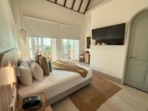 a bedroom with a bed with pillows and a tv at Casa Bugó Arsenal Hotel Boutique en Getsemaní in Cartagena de Indias