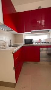 a kitchen with red cabinets and a sink at Messapia Homes in Mesagne