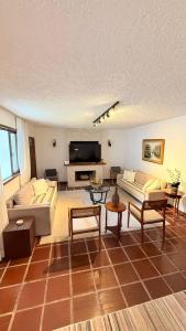 a living room with couches and a flat screen tv at Refúgio na Serra - natureza e conforto in Teresópolis