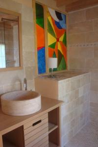 a bathroom with a sink and a painting on the wall at Les Petites Maïs in Nantes-en-Rattier