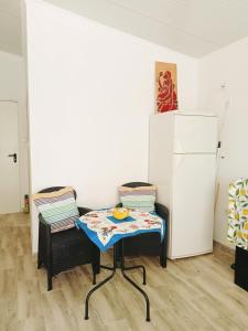 a table and two chairs in a room with a refrigerator at Estúdio ensolarado in Fernao Ferro