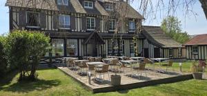a group of tables and chairs in front of a house at Logis Auberges des Aulnettes in Houlgate +17 photos