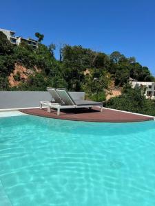 a pool with two lounge chairs next to the water at Blue Sky Condo by Palmetto Karon in Ka Rorn