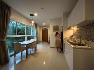 a woman is standing in a kitchen with a table at Blue Sky Condo by Palmetto Karon in Ka Rorn