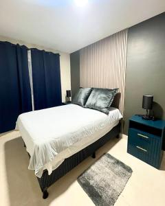 a bedroom with a large bed with blue curtains at Rest and Reset in Usulután