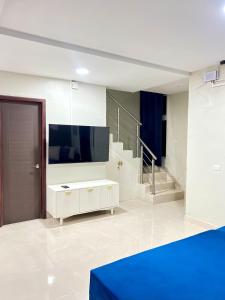 a living room with a flat screen tv and stairs at Rest and Reset in Usulután