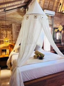 a bedroom with a canopy bed with a bowl of fruit on it at Joglo Ulu Home in Uluwatu +35 photos