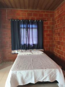 a bed in a brick room with a window at Kitnet Rústica! in Januária