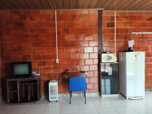 a brick wall with a refrigerator and a table and chair at Kitnet Rústica! in Januária