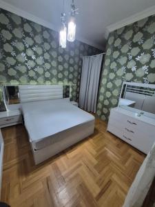 a bedroom with a white bed and a wooden floor at Milo Comfort 2 in Rustavi