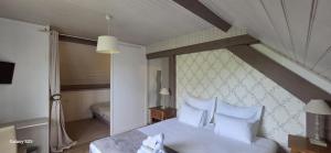 a bedroom with a bed with white sheets and pillows at Logis Auberges des Aulnettes in Houlgate