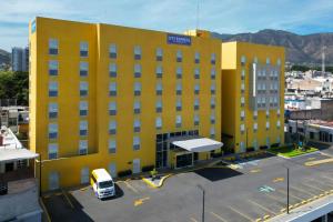a yellow building with a van parked in a parking lot at City Express by Marriott Tepic in Tepic