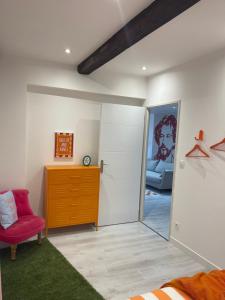 a bedroom with a red chair and a dresser at Le pop Daudet in Fontvieille