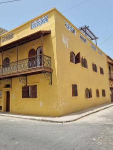 a yellow building with a balcony on the side of it at Maison Sakeena in Saint-Louis