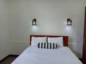 a bed with a black and white pillow on it at Misty Edge Hanthana in Kandy