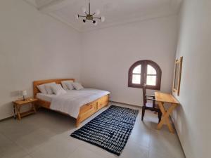 a bedroom with a bed and a table and a window at Maison Sakeena in Saint-Louis