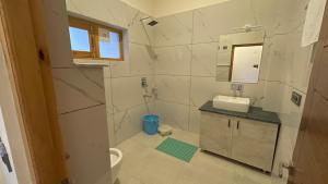 a bathroom with a toilet and a sink and a mirror at Hotel shaynam in Leh +35 photos