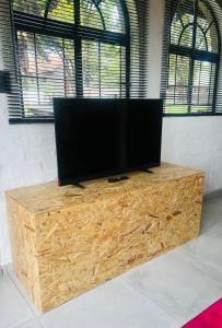 a flat screen tv sitting on top of a wooden stand at Origin Cottage in eMalahleni