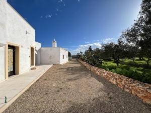an external view of a white building with a stone wall at Giù al Vigneto in Leporano
