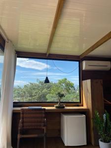a window in a room with a table and a tree at Suítes Âncora Praia do Rosa in Imbituba +1 photo