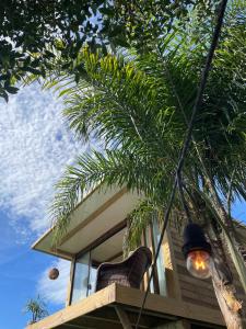 a house with a chair and a palm tree at Suítes Âncora Praia do Rosa in Imbituba