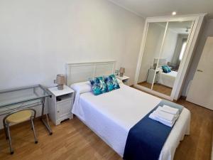 a bedroom with a bed and a desk and a mirror at Playa Jardin Boiro in Boiro