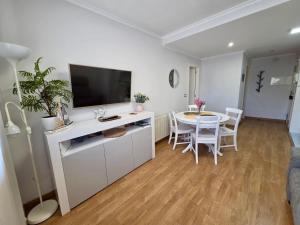 a living room with a table and a flat screen tv at Playa Jardin Boiro in Boiro