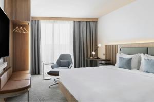 a hotel room with a large bed and a chair at Courtyard by Marriott Biel Bienne in Biel +93 photos