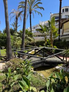 a bridge over a creek in a park with palm trees at Anais Marbella in Marbella