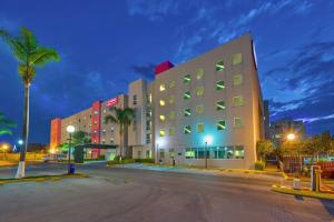 a large building with palm trees in front of it at City Express Suites by Marriott Queretaro in Querétaro