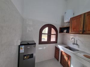 a small kitchen with a refrigerator and a sink at Maison Sakeena in Saint-Louis