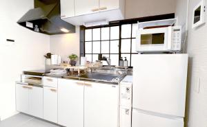 a white kitchen with a sink and a microwave at 紡ぎの宿 桜 - 民泊 - Tsumugi no Yado SAKURA in Abiko