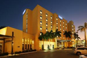 a hotel with palm trees in front of a parking lot at City Express by Marriott Tampico in Tampico