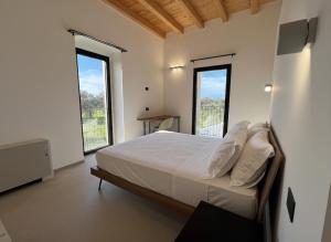 a bedroom with a bed and two large windows at Giù al Vigneto in Leporano