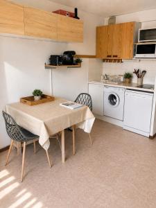 a kitchen with a table and chairs and a washing machine at Vue montagne exceptionnelle T2 Cosy avec Balcon proche du lac in Embrun