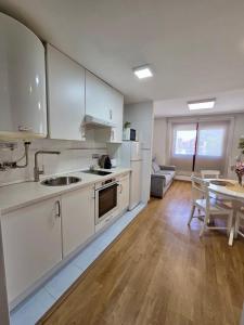 a kitchen with white cabinets and a table and a dining room at Playa Jardin Boiro in Boiro