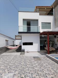 a house with a patio and a hammock at Los Pulpos Beach House in Bombiso