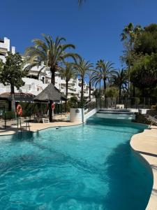 a swimming pool with blue water and palm trees at Anais Marbella in Marbella +45 photos