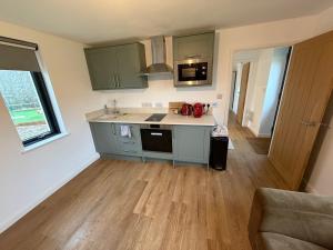 a kitchen with green cabinets and a wooden floor at The Bat Barn in Corsley