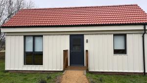 a small white house with a red roof at The Bat Barn in Corsley