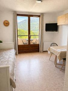 a room with a bed and a sliding glass door at Vue montagne exceptionnelle T2 Cosy avec Balcon proche du lac in Embrun
