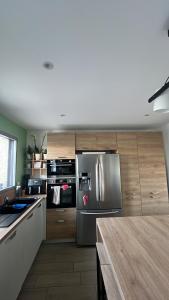 a kitchen with a stainless steel refrigerator and wooden cabinets at Chez TIKA in Saint-Lager