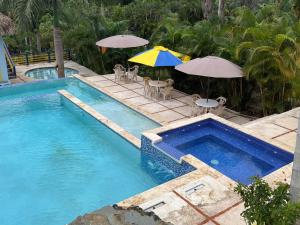 a swimming pool with two umbrellas and chairs and a table with an umbrella at Segundo Piso complet in La Cuaba