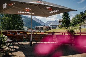 a patio with an umbrella and tables and chairs at Bergblick - der Gasthof in Riezlern