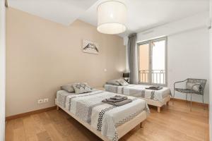 a white room with two beds and a chair at 10 Rue de la Rampe in Cannes