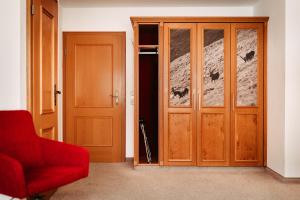 a room with a red chair and two wooden doors at Bergblick - der Gasthof in Riezlern