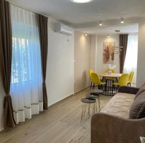 a living room with a couch and a table and yellow chairs at Vila Ideal in Donji Štoj