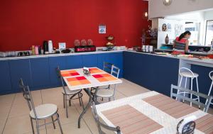 a restaurant with a table and chairs and a woman in the kitchen at Acqua Flats Jaguariúna in Jaguariúna +20 photos